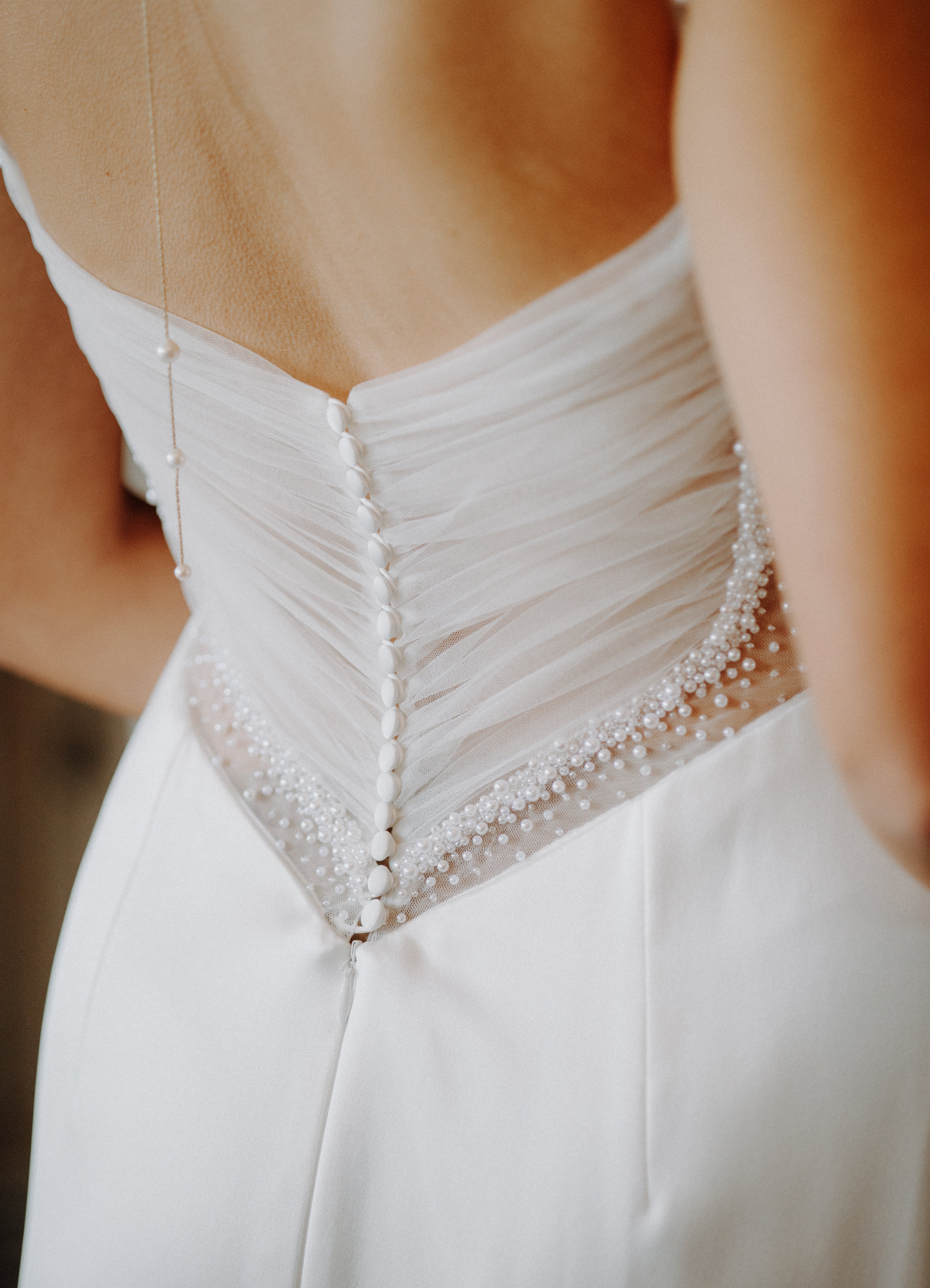 Minimalistisches Brautkleid mit Spaghettiträgern, Beinschlitz und luxuriösem Satin, der sich in einem perlig fallenden Rückendetail zeigt – moderne Eleganz für die Braut.