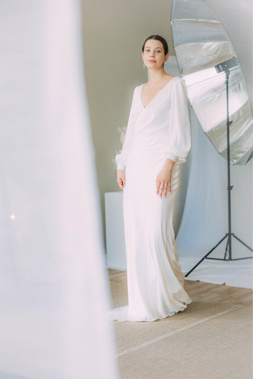 Elegante Braut in Satin-Hochzeitskleid mit langen Bischofsärmeln, offenem Rücken und seitlichem Schlitz im Rock, Brautmode Hamburg