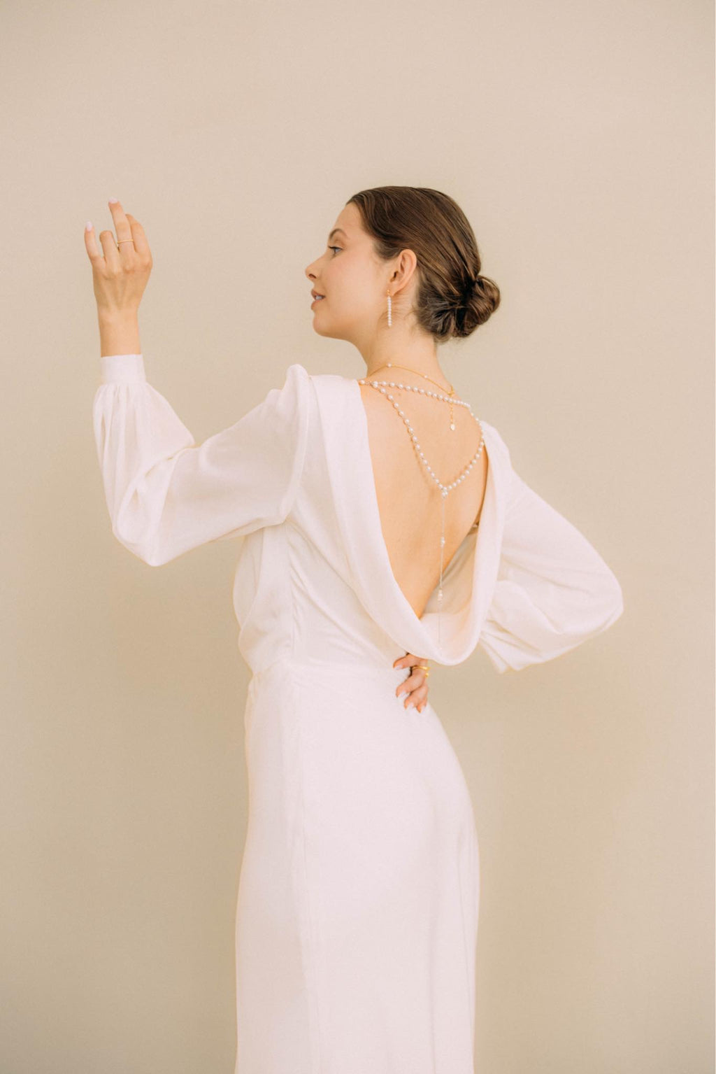 Elegante Braut in Satin-Hochzeitskleid mit langen Bischofsärmeln, offenem Rücken und seitlichem Schlitz im Rock, Brautmode Hamburg