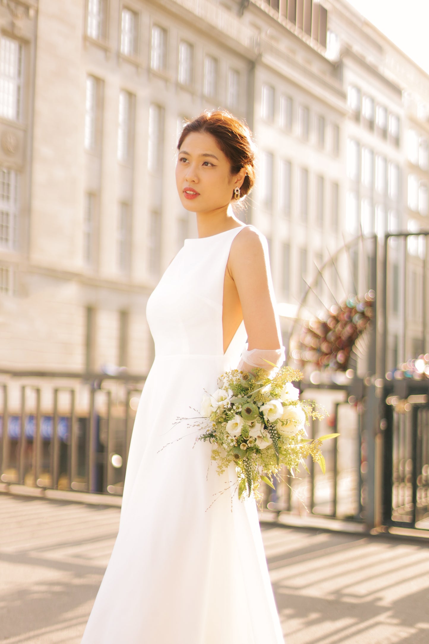 Elegante Braut in ärmellosem Hochzeitskleid aus Satin mit transparenten Seiten, Hamburg.