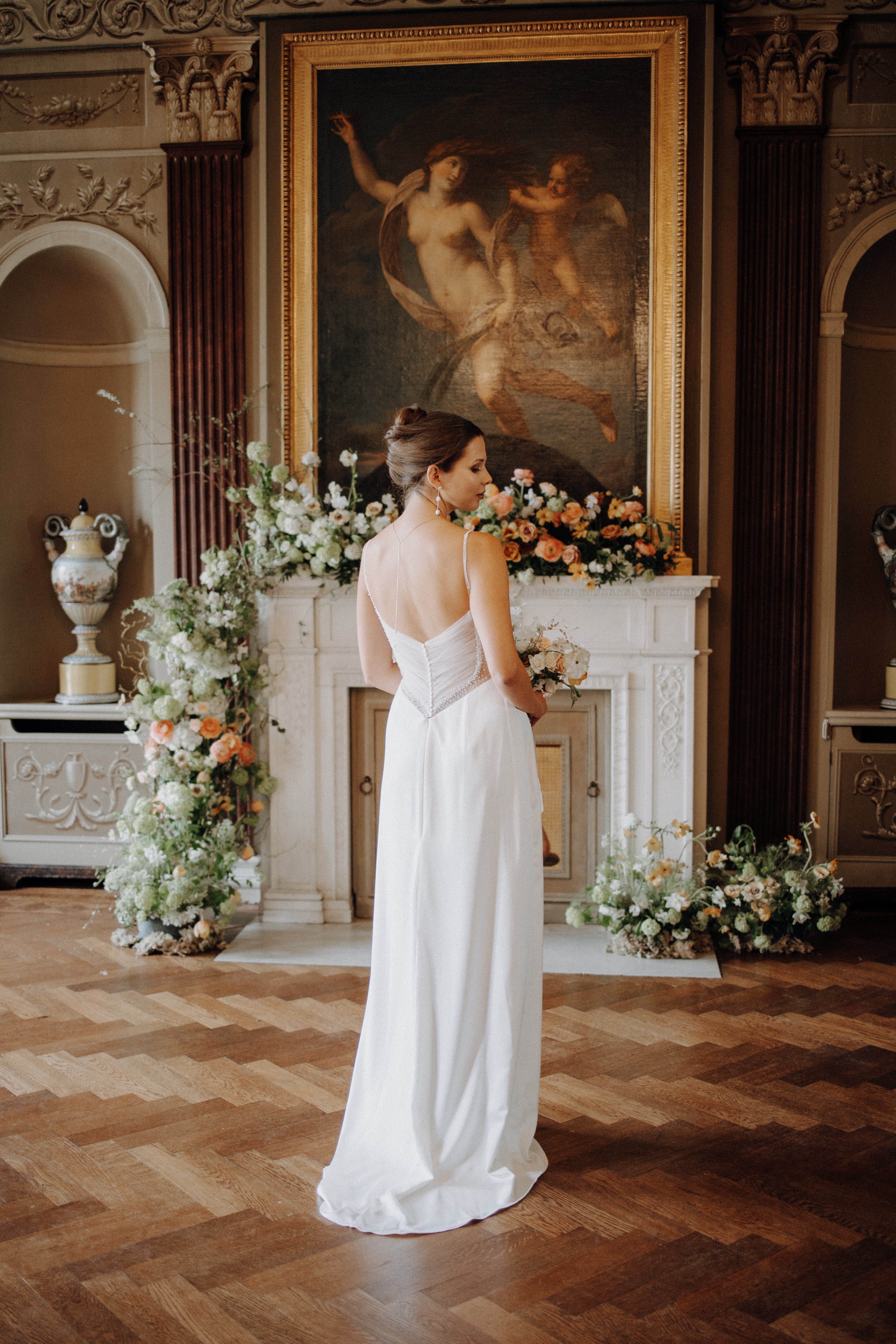Minimalistisches Brautkleid mit Spaghettiträgern, Beinschlitz und luxuriösem Satin, der sich in einem perlig fallenden Rückendetail zeigt – moderne Eleganz für die Braut.