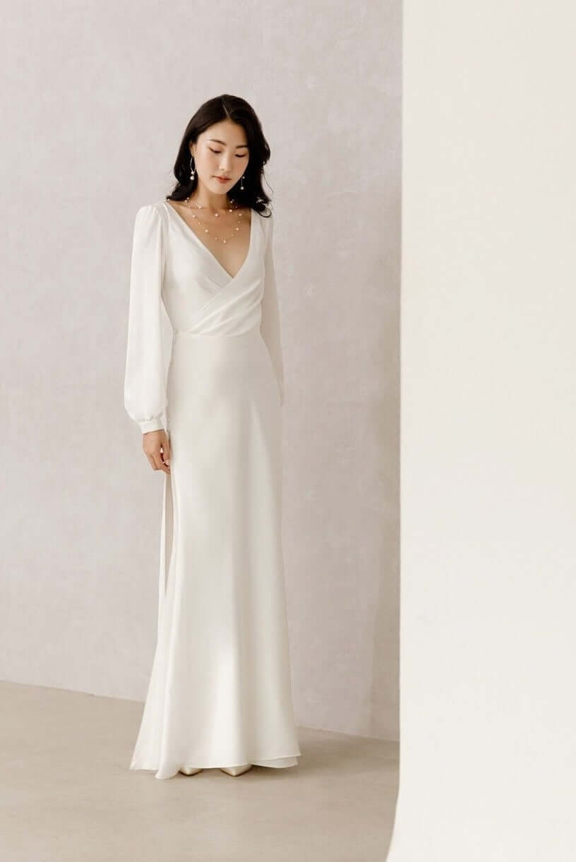 Elegante Braut in Satin-Hochzeitskleid mit langen Bischofsärmeln, offenem Rücken und seitlichem Schlitz im Rock, Hamburg