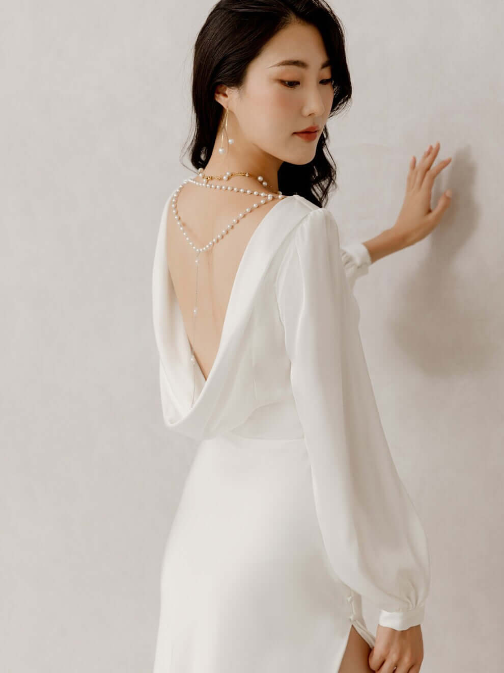 Elegante Braut in Satin-Hochzeitskleid mit langen Bischofsärmeln, offenem Rücken und seitlichem Schlitz im Rock, Hamburg