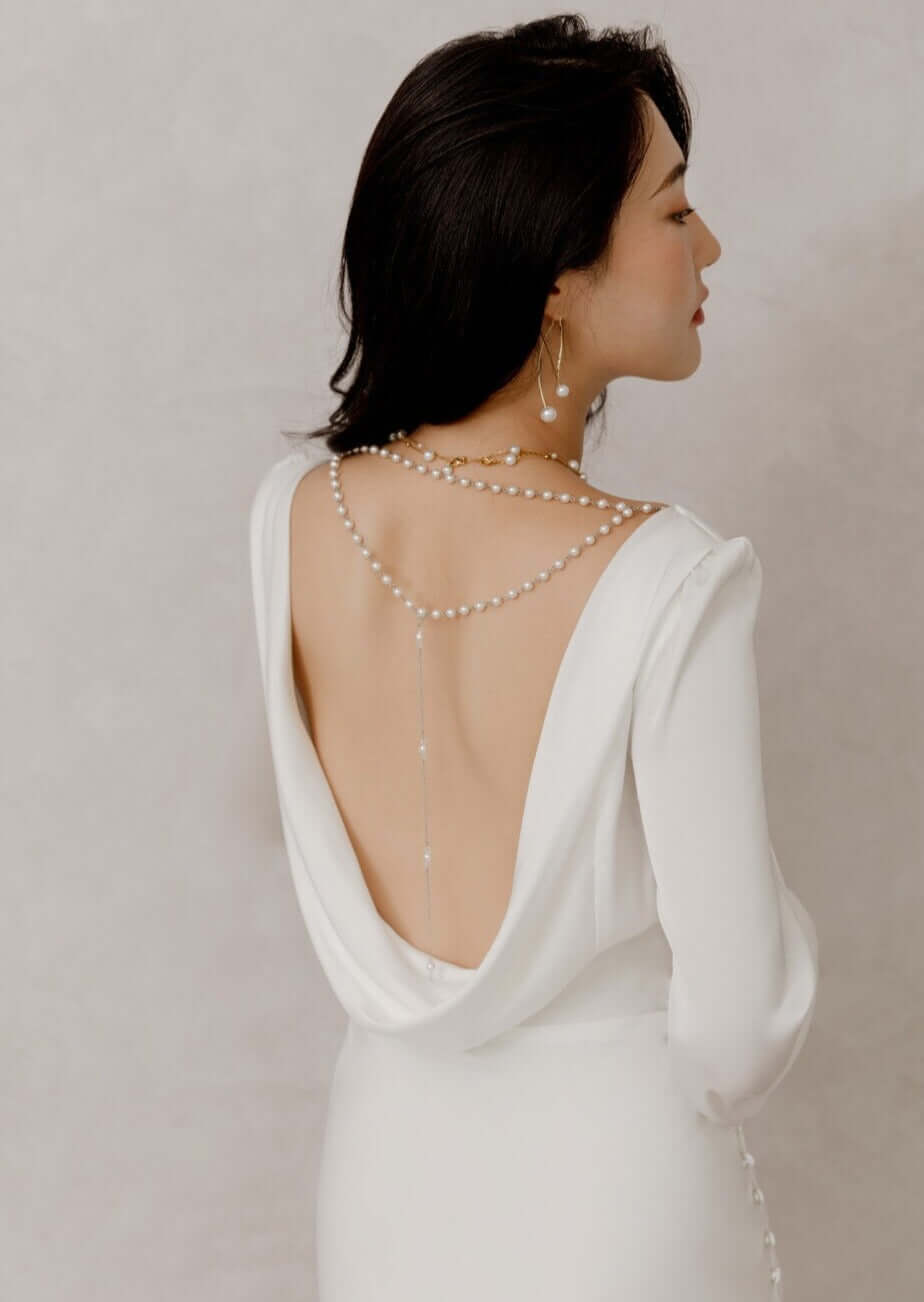 Elegante Braut in Satin-Hochzeitskleid mit langen Bischofsärmeln, offenem Rücken und seitlichem Schlitz im Rock, Hamburg