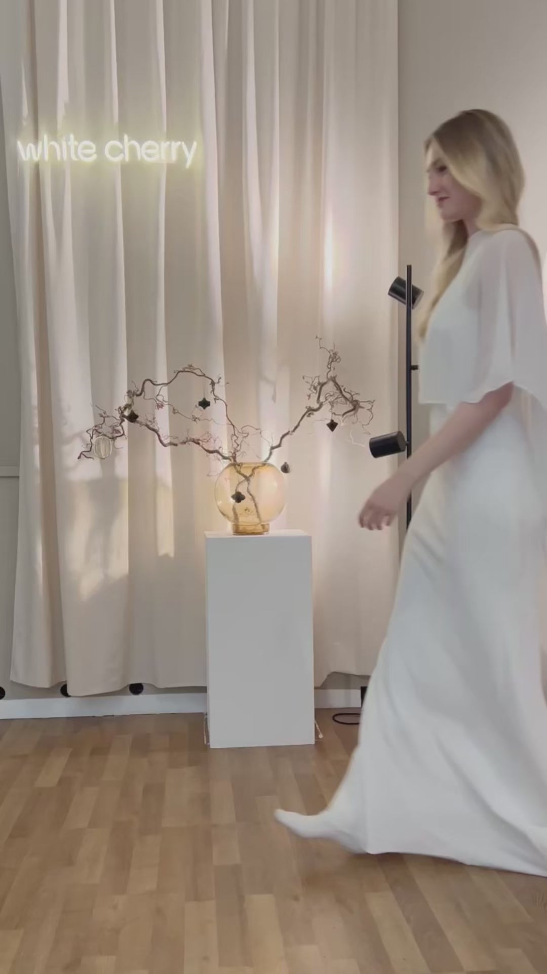 Sheer white chiffon wedding cape flowing softly over the shoulders, adding a delicate and ethereal touch to the bridal look Zarter, transparenter Chiffon-Brautcape in Weiß, der sanft über die Schultern fällt und dem Brautlook eine elegante, ätherische Note verleiht.