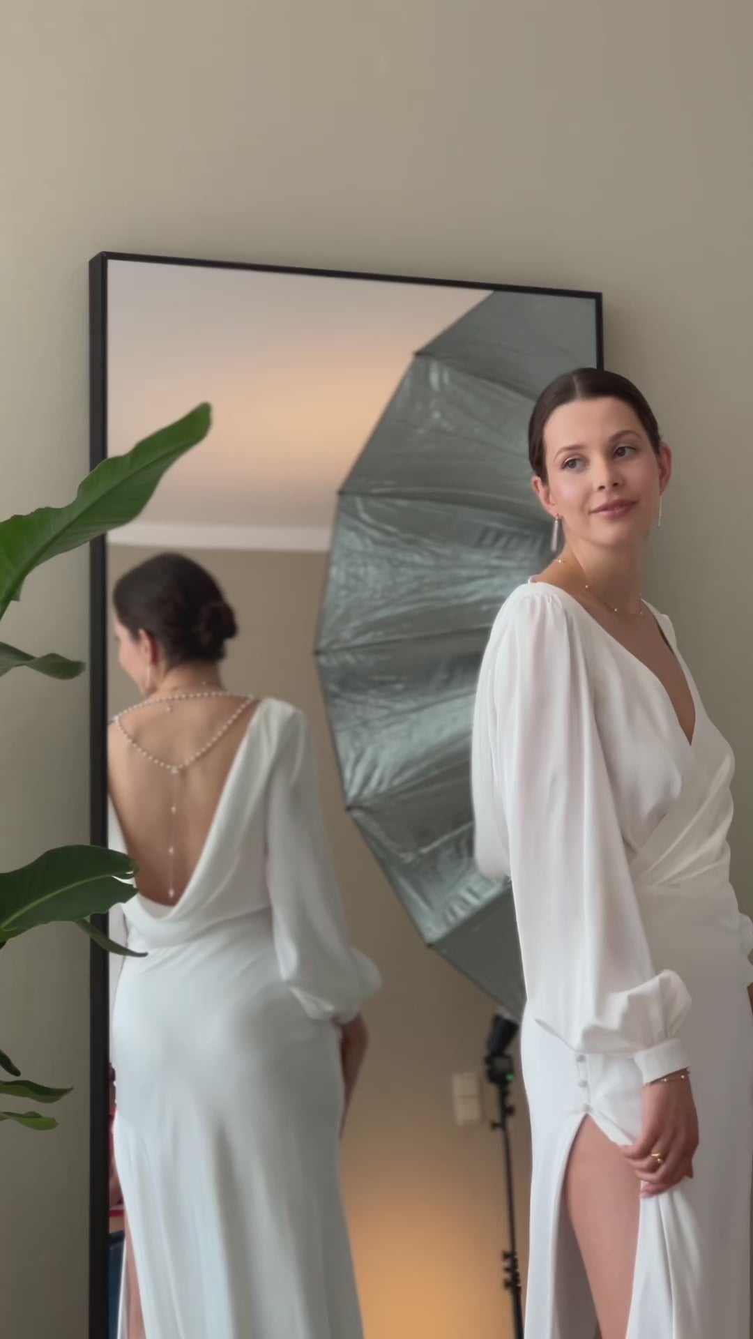 Elegante Braut in Satin-Hochzeitskleid mit langen Bischofsärmeln, offenem Rücken und seitlichem Schlitz im Rock, Brautmode Hamburg
